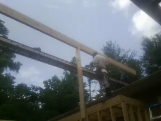 Carpenter setting a ridge beam over a new addition frame — Ice Dam Removal by Roofing Brothers in Alexander